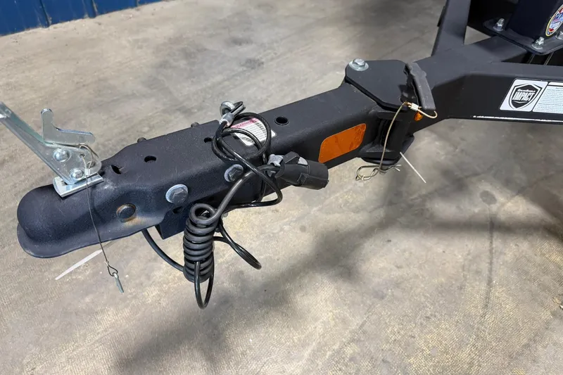 Slide: The Image of 2024 Tahoe T18 trailer hitch with safety cables and locking mechanism on concrete floor. - 36