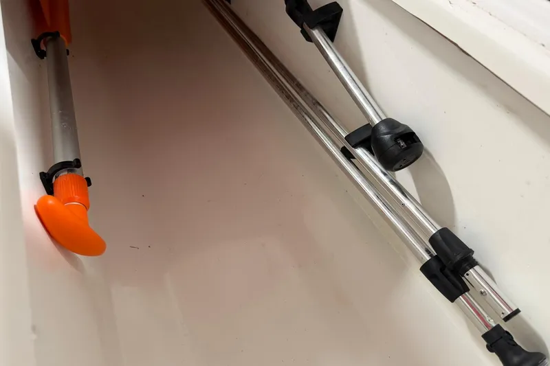 Slide: The Image of Storage compartment in a 2024 Tahoe T18 boat with metal poles and orange handle. - 8