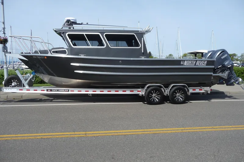 The Image of 2025 North River 2700s boat on trailer, parked on a street near a marina. - 0