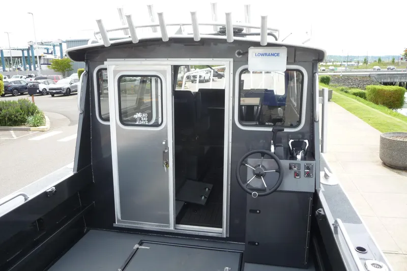 Slide: The Image of 2025 North River 2700s boat with steering wheel and cabin door, docked outdoors. - 12