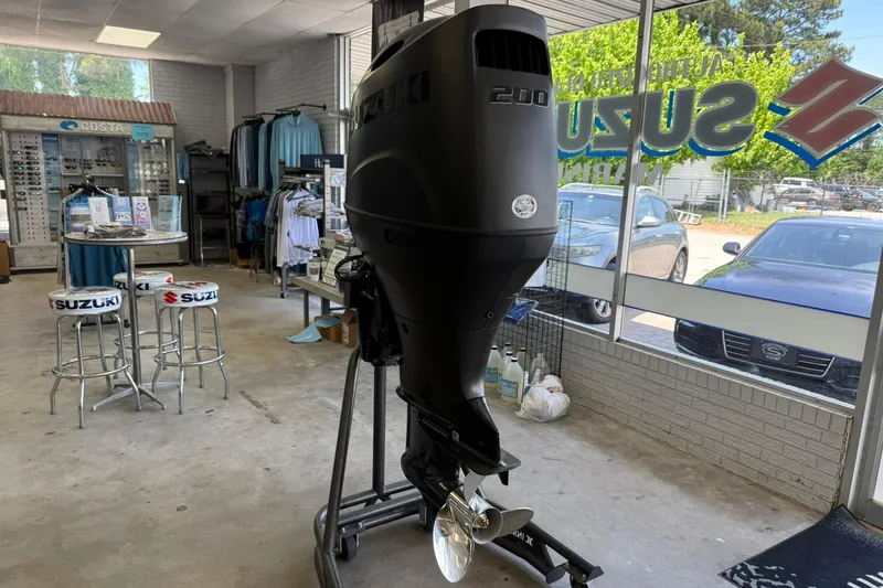 Slide: The Image of Suzuki outboard motor displayed in a showroom with Suzuki-branded stools and apparel. - 13