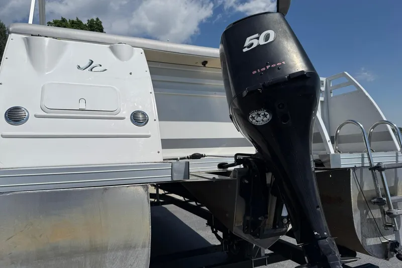 Slide: The Image of 2010 JC 21 Neptoon pontoon boat with 50 HP BigFoot motor, under a clear blue sky. - 3