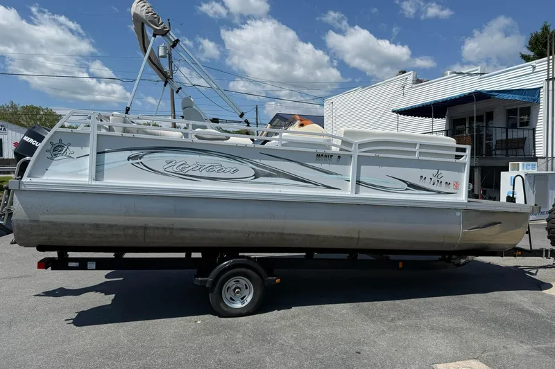 Slide: The Image of 2010 JC 21 Neptoon pontoon boat on trailer under clear blue sky. - 4