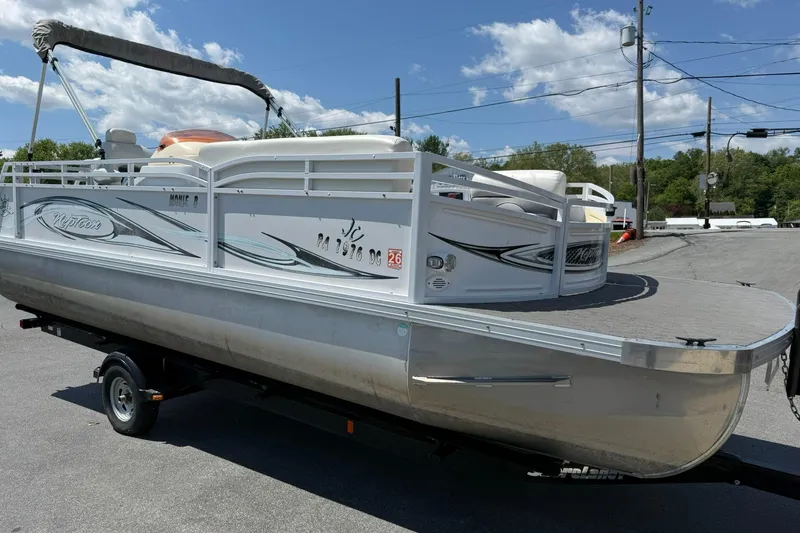 Slide: The Image of 2010 JC 21 Neptoon pontoon boat on trailer under a clear blue sky. - 5