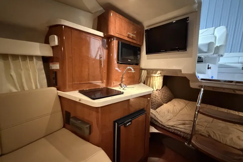 Slide: The Image of Interior of a 2012 Regal 28 Express boat featuring a compact kitchen and cozy sleeping area. - 24