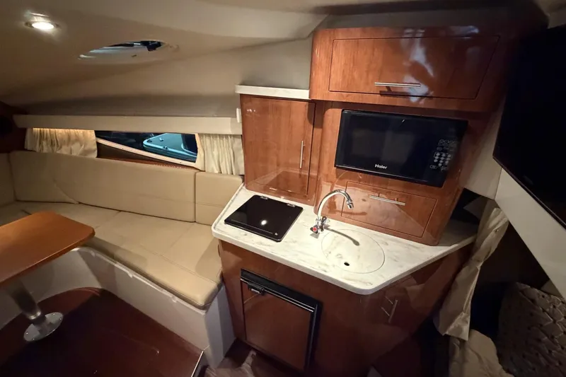 Slide: The Image of Interior of a 2012 Regal 28 Express boat featuring a compact kitchen and seating area. - 25