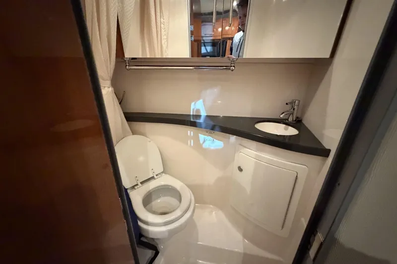 Slide: The Image of Compact bathroom in a 2012 Regal 28 Express boat, featuring a toilet and sink. - 29