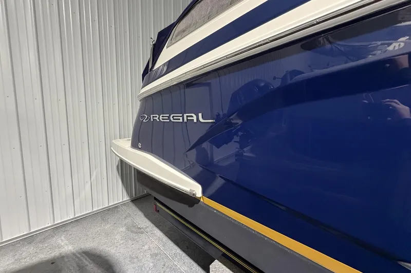 Slide: The Image of 2012 Regal 28 Express boat, blue hull, parked indoors, side view. - 3