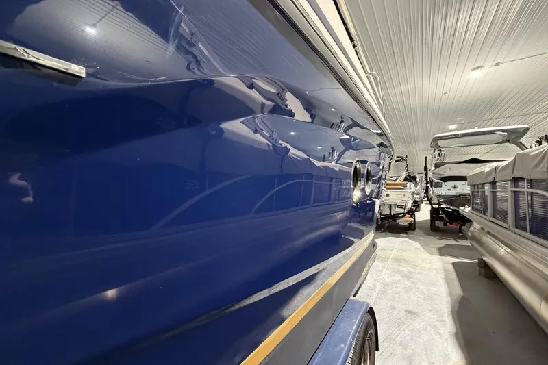 Slide: The Image of 2012 Regal 28 Express boat in indoor storage, showcasing sleek blue hull design. - 4
