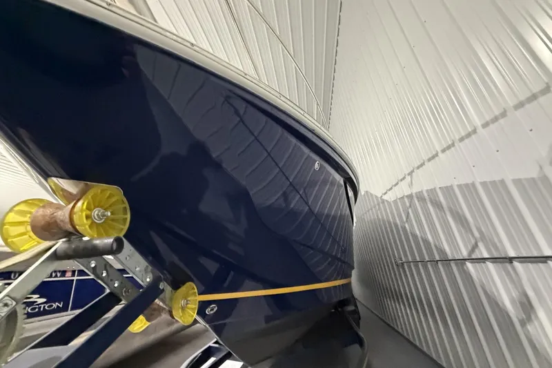 Slide: The Image of 2012 Regal 28 Express boat in storage, showcasing sleek blue hull and yellow stripe. - 7