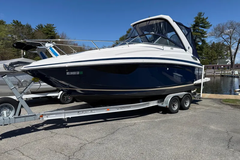 Slide: The Image of 2018 Regal 28 Express boat on trailer, parked near a lake under clear blue sky. - 2