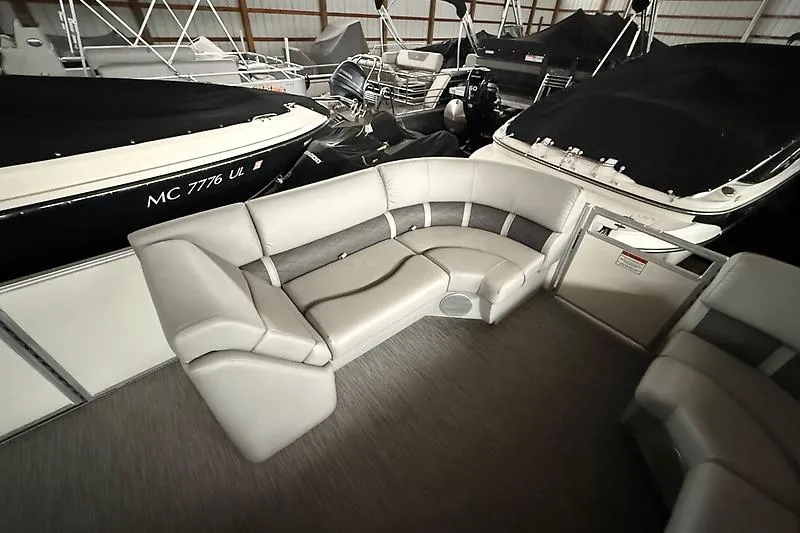 Slide: The Image of 2021 Bennington 25 SSBXSD pontoon boat interior with plush seating in a showroom. - 11