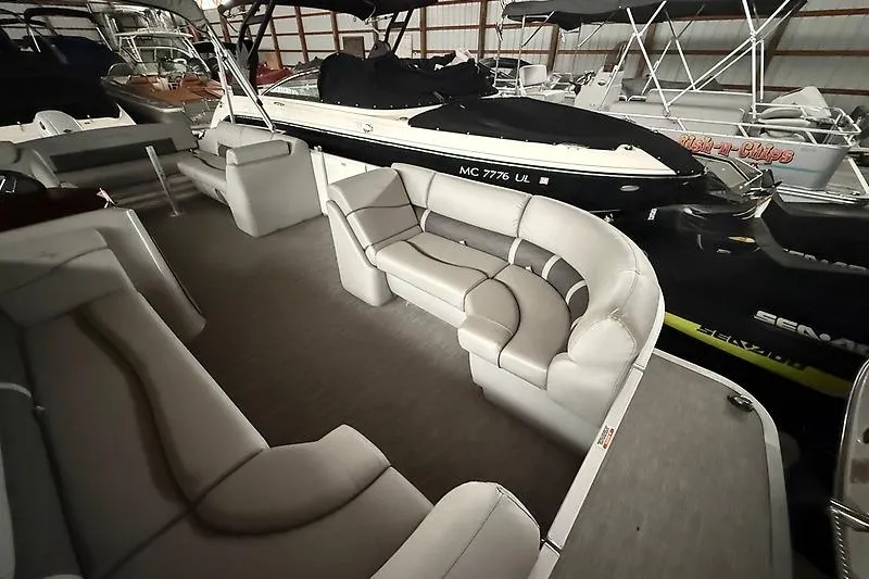 Slide: The Image of 2021 Bennington 25 SSBXSD pontoon boat interior with plush seating in a storage facility. - 13