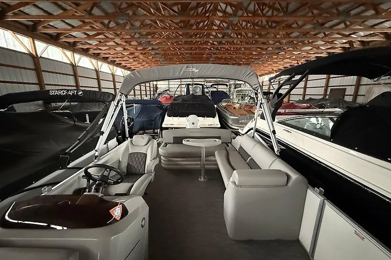Slide: The Image of 2021 Bennington 25 SSBXSD pontoon boat in storage, featuring spacious seating and canopy. - 18