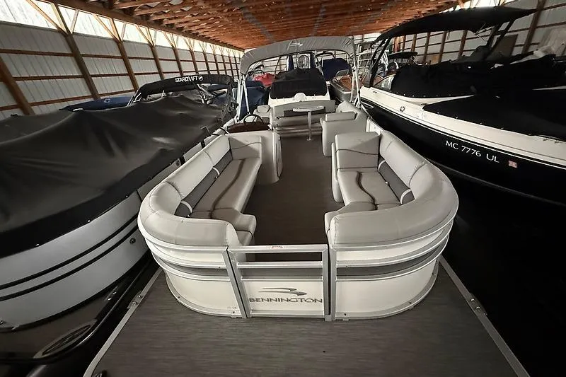 Slide: The Image of 2021 Bennington 25 SSBXSD pontoon boat in covered storage, featuring spacious seating. - 19