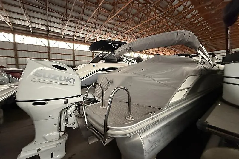 Slide: The Image of 2021 Bennington 25 SSBXSD pontoon boat with Suzuki outboard motor in storage. - 2