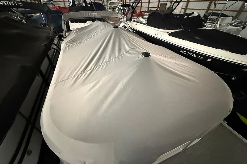 Slide: The Image of 2021 Bennington 25 SSBXSD boat covered in storage, showcasing protective cover. - 6