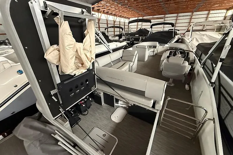 Slide: The Image of 2021 Bennington 25 SSBXSD pontoon boat interior in storage, showcasing seating and helm. - 7