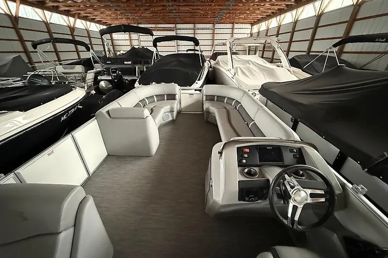 Slide: The Image of 2021 Bennington 25 SSBXSD pontoon boat interior in storage, featuring spacious seating and helm. - 9