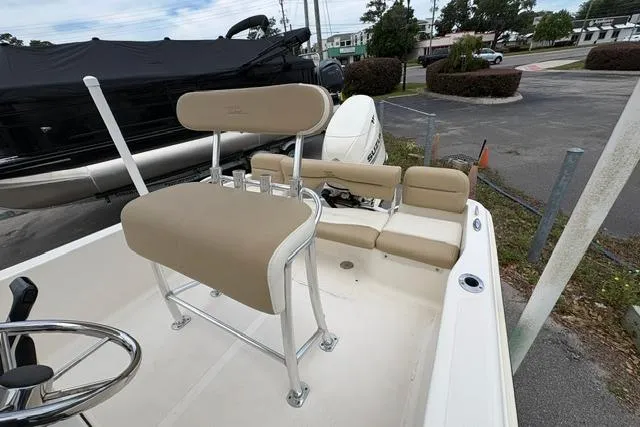 Slide: The Image of 2020 Pioneer 180 Islander boat with beige seating and steering wheel, parked outdoors. - 3