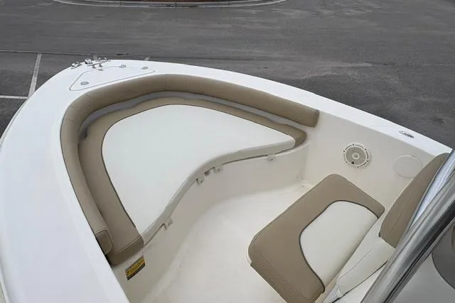 Slide: The Image of 2020 Pioneer 180 Islander boat interior with cushioned seating in a parking lot. - 6