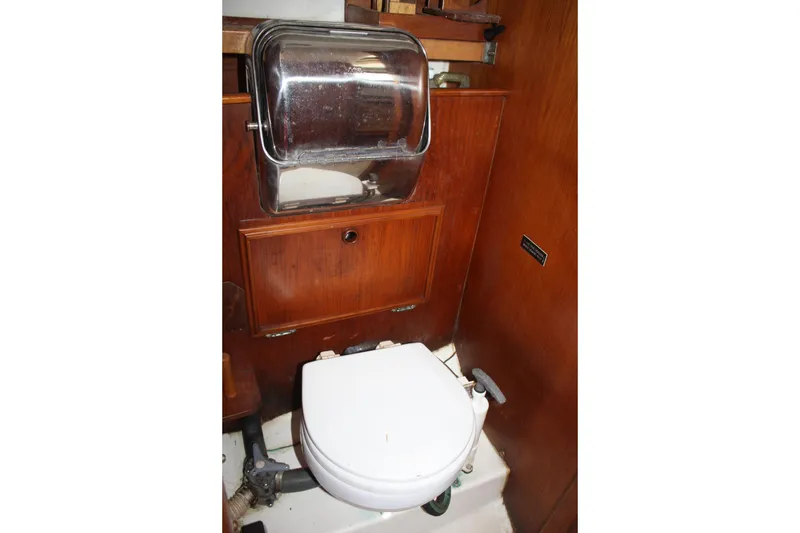 Slide: The Image of 1983 Cape Dory 27 boat bathroom with wooden cabinetry and compact toilet. - 21