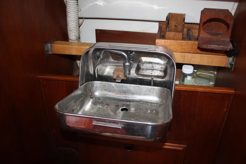 Slide: The Image of Stainless steel sink in 1983 Cape Dory 27 sailboat interior, with wooden shelving. - 24