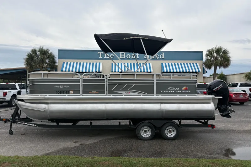 The Image of 2023 Sun Tracker Party Barge 22 DLX pontoon boat on trailer outside dealership. - 0