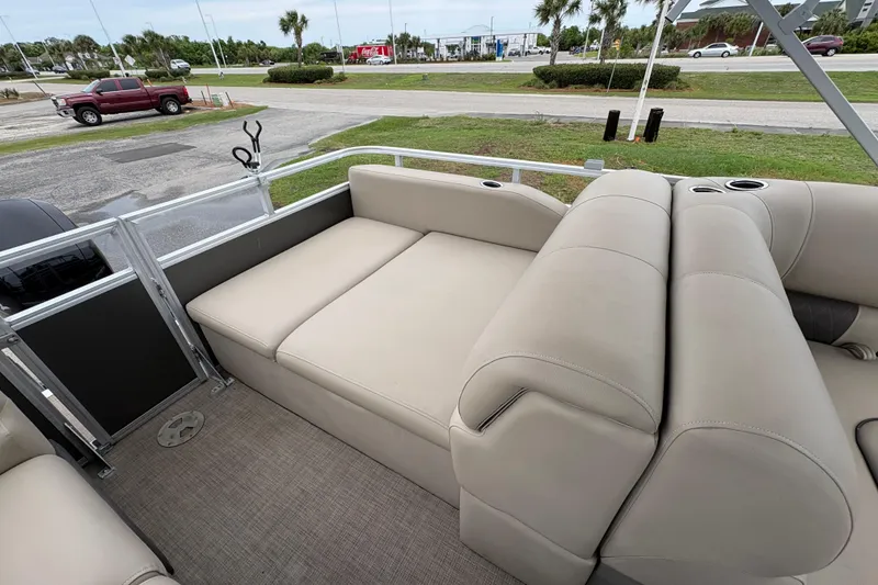 Slide: The Image of 2023 Sun Tracker Party Barge 22 DLX interior with beige seating and cup holders. - 10
