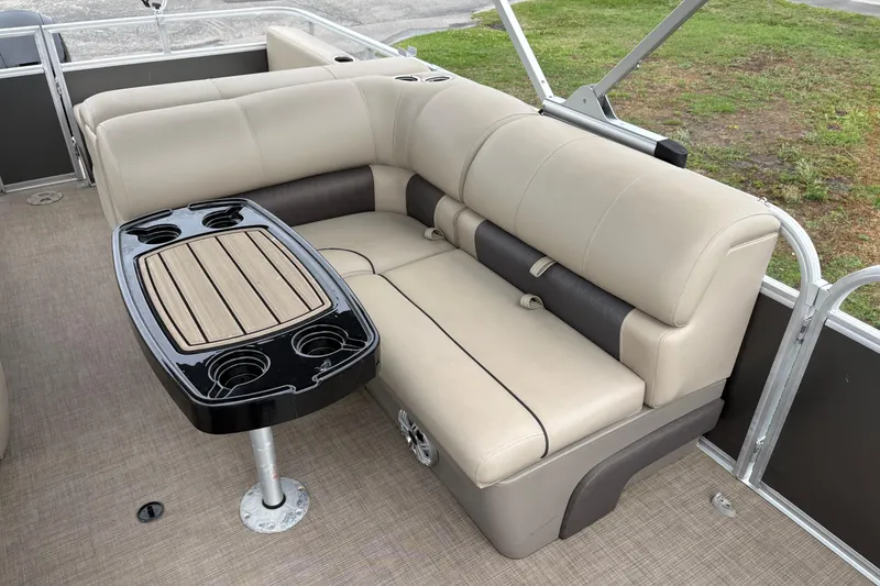 Slide: The Image of 2023 Sun Tracker Party Barge 22 DLX interior with beige seating and a sleek table. - 16