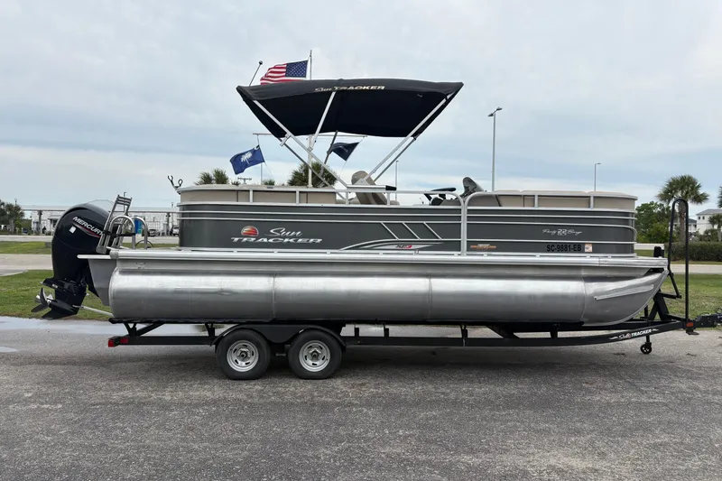 Slide: The Image of 2023 Sun Tracker Party Barge 22 DLX pontoon boat on trailer, parked outdoors. - 4