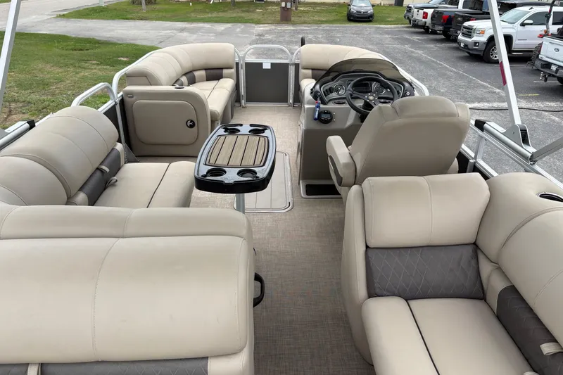 Slide: The Image of 2023 Sun Tracker Party Barge 22 DLX interior with beige seating and steering console. - 8