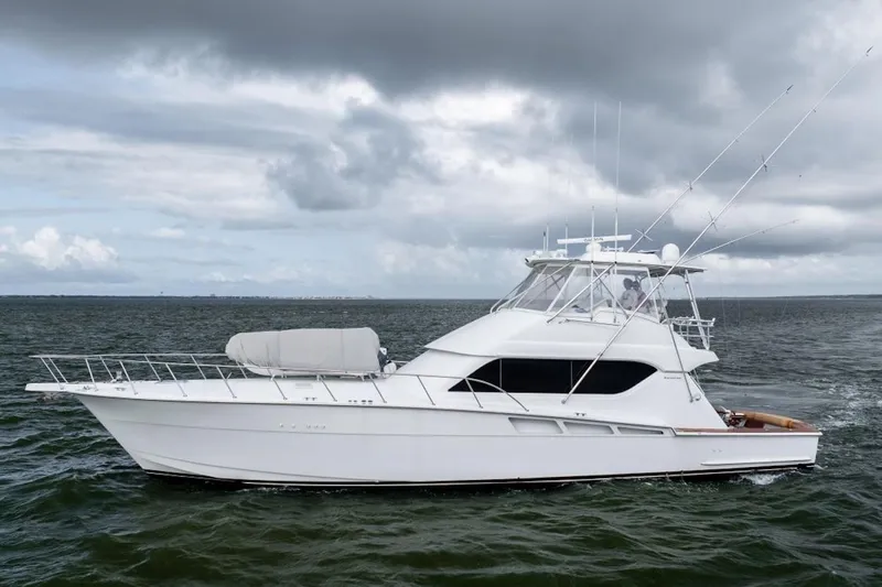 The Image of 2003 Hatteras 60 Convertible yacht cruising on open water under cloudy skies. - 4