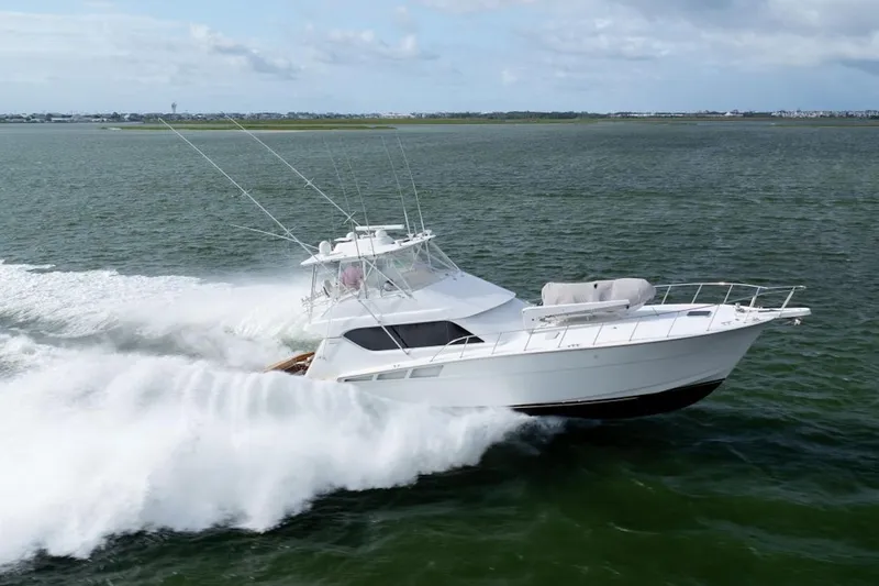 Slide: The Image of 2003 Hatteras 60 Convertible yacht cruising swiftly on open water. - 6