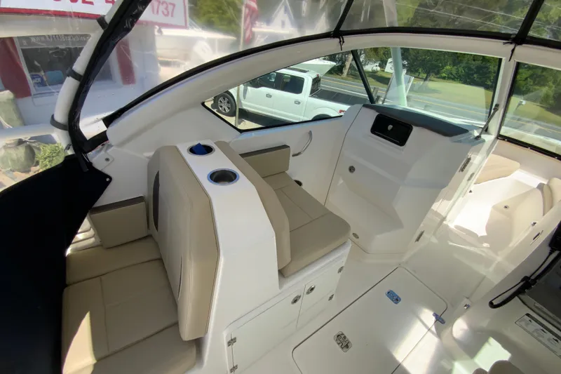 Slide: The Image of 2021 Pursuit DC 266 Dual Console interior with beige seating and cup holders. - 16