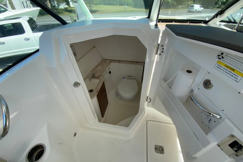 Slide: The Image of 2021 Pursuit DC 266 Dual Console boat interior with compact marine toilet. - 21