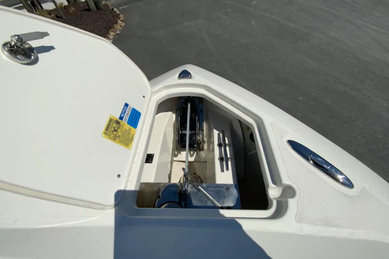 Slide: The Image of 2021 Pursuit DC 266 Dual Console anchor compartment with open hatch, showcasing storage space. - 26