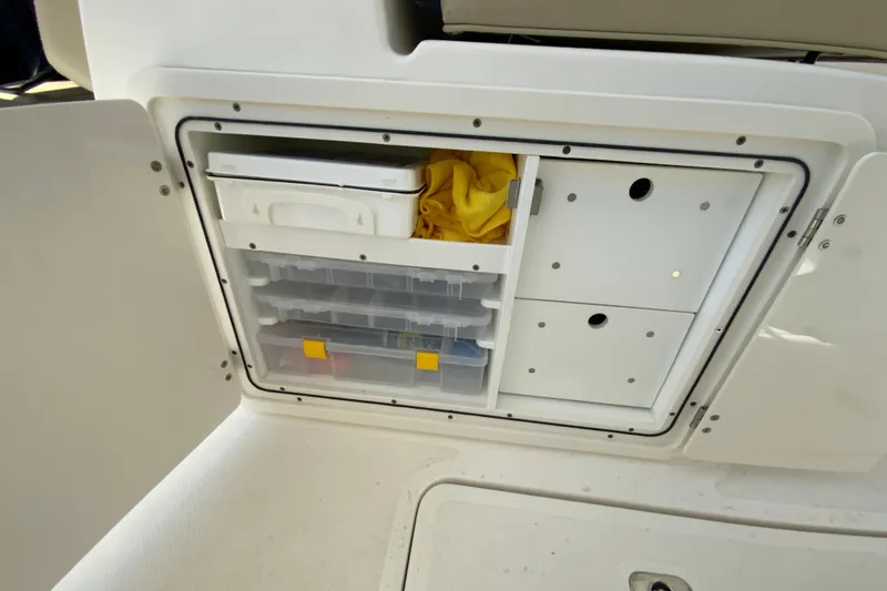 Slide: The Image of Storage compartment on a 2021 Pursuit DC 266 Dual Console boat, featuring organized shelves and containers. - 30