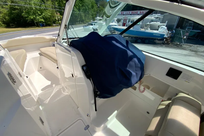 Slide: The Image of 2021 Pursuit DC 266 Dual Console interior with covered helm, beige seating, and outdoor view. - 35