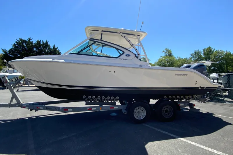 Slide: The Image of 2021 Pursuit DC 266 Dual Console boat on trailer, parked outdoors. - 6