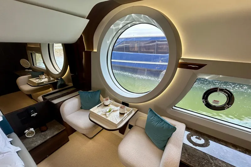 Slide: The Image of Luxurious interior of 2024 Aicon Vivere 66 yacht with elegant seating and large circular windows. - 66