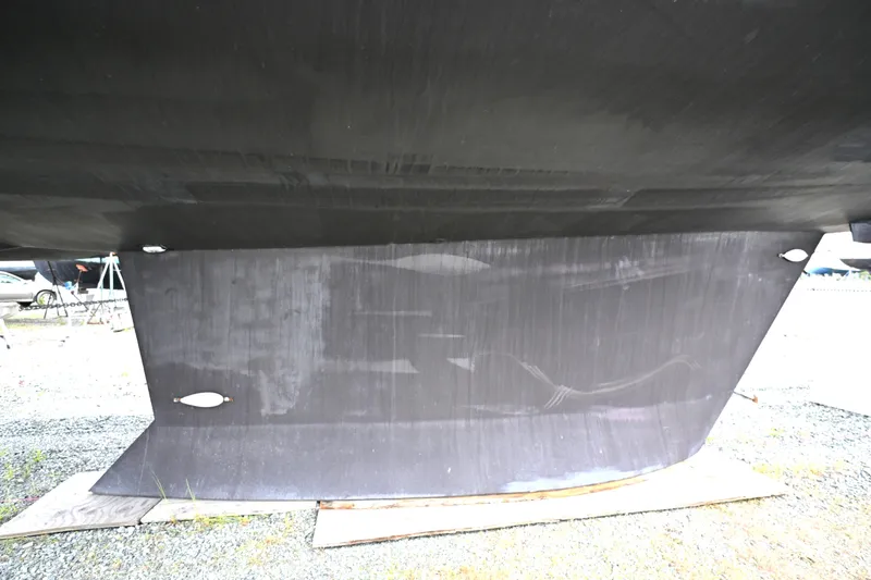 Slide: The Image of Underside view of a 2006 Waterline 50 boat hull on a gravel surface. - 118