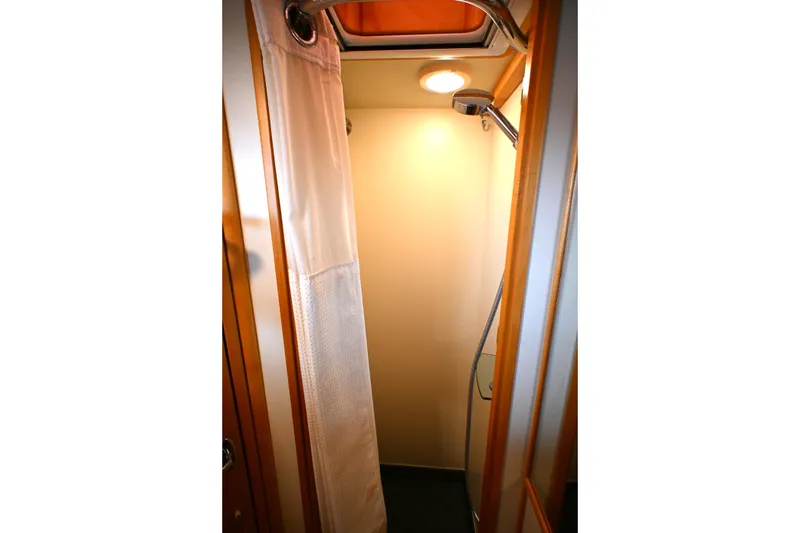 Slide: The Image of Compact shower area in a 2006 Waterline 50 yacht, featuring a curtain and overhead light. - 67