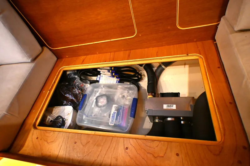 Slide: The Image of Under-seat storage compartment in a 2006 Waterline 50 yacht, containing various equipment and supplies. - 90