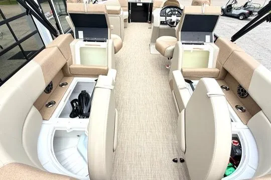 Slide: The Image of 2026 Manitou Aurora RF 23 boat interior with beige seating and storage compartments. - 12