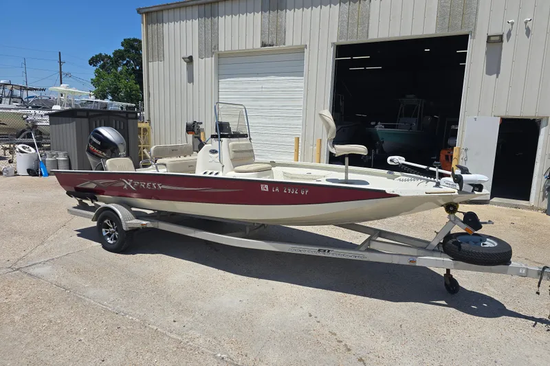The Image of 2016 Xpress H20B Bay boat on trailer outside a garage. - 1