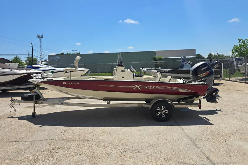 Slide: The Image of 2016 Xpress H20B Bay boat on trailer, parked outdoors under clear blue sky. - 6