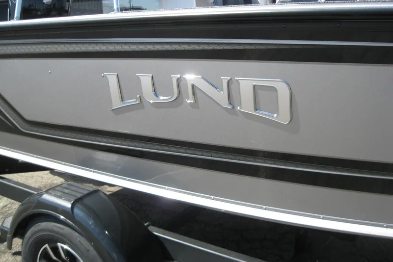 Slide: The Image of 2026 Lund 1875 Impact XS Sport boat, close-up of logo on sleek exterior. - 11
