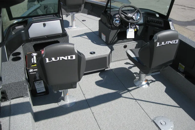 Slide: The Image of 2026 Lund 1875 Impact XS Sport boat interior with steering wheel and branded seats. - 15