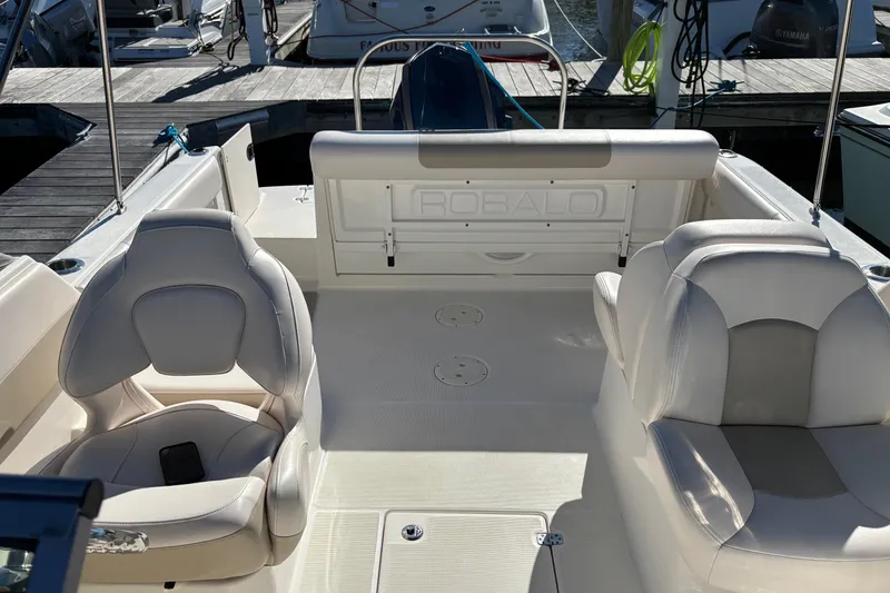 Slide: The Image of 2017 Robalo R227 Dual Console boat interior with white seating at a marina. - 16